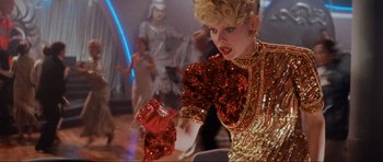 Movie still from “Indiana Jones and the Temple of Doom” (1984), directed by Steven Spielberg – A woman in a red and gold dress holding a red purse; Medium shot, Low angle