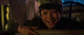 Movie still from “Indiana Jones and the Temple of Doom” (1984), directed by Steven Spielberg – A boy with a hat is smiling for the camera; Close Up shot, Overhead angle