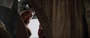 Movie still from “Indiana Jones and the Temple of Doom” (1984), directed by Steven Spielberg – A man with a beard wearing a hat and holding a curtain; Close Up shot, Low angle