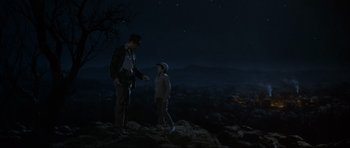 Movie still from “Indiana Jones and the Temple of Doom” (1984), directed by Steven Spielberg – A man and a boy standing on top of a hill at night; Wide shot, Low angle