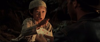Movie still from “Indiana Jones and the Temple of Doom” (1984), directed by Steven Spielberg – A young boy is playing cards with another person; Close Up shot, Over the shoulder angle