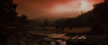 Movie still from “Indiana Jones and the Temple of Doom” (1984), directed by Steven Spielberg – A group of people standing on top of rocks next to a river; Extreme Wide shot, High angle