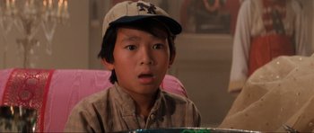 Movie still from “Indiana Jones and the Temple of Doom” (1984), directed by Steven Spielberg – A boy wearing a baseball cap and a plaid shirt; Close Up shot, High angle