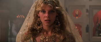 Movie still from “Indiana Jones and the Temple of Doom” (1984), directed by Steven Spielberg – A woman with long blonde hair wearing a veil and gold jewelry; Close Up shot, Low angle