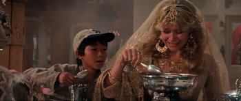 Movie still from “Indiana Jones and the Temple of Doom” (1984), directed by Steven Spielberg – A young boy and a woman are stirring something in a bowl; Close Up shot, Over the shoulder angle