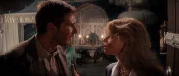 Movie still from “Indiana Jones and the Temple of Doom” (1984), directed by Steven Spielberg – A man and a woman face to face in a dark room; Medium shot, Over the shoulder angle