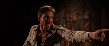 Movie still from “Indiana Jones and the Temple of Doom” (1984), directed by Steven Spielberg – A person standing in front of a painting; Close Up shot, Over the shoulder angle