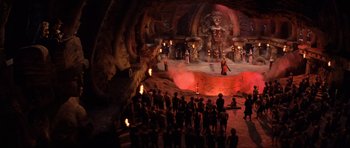Movie still from “Indiana Jones and the Temple of Doom” (1984), directed by Steven Spielberg – A group of people standing in front of a stage; Extreme Wide shot, High angle