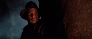 Movie still from “Indiana Jones and the Temple of Doom” (1984), directed by Steven Spielberg – A man wearing a hat standing next to a tree; Close Up shot, Low angle
