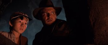 Movie still from “Indiana Jones and the Temple of Doom” (1984), directed by Steven Spielberg – A person wearing a hat and a jacket; Close Up shot, Low angle