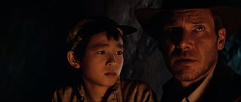 Movie still from “Indiana Jones and the Temple of Doom” (1984), directed by Steven Spielberg – A boy and a man in a dark room; Close Up shot, Low angle