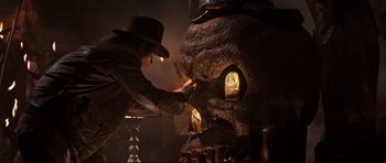 Movie still from “Indiana Jones and the Temple of Doom” (1984), directed by Steven Spielberg – A man in a cowboy hat is touching a skull; Close Up shot, Low angle