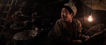 Movie still from “Indiana Jones and the Temple of Doom” (1984), directed by Steven Spielberg – A young man sitting in front of a basket; Close Up shot, High angle