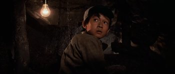 Movie still from “Indiana Jones and the Temple of Doom” (1984), directed by Steven Spielberg – A young boy wearing a hat and a jacket; Close Up shot, Low angle