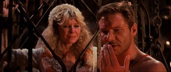 Movie still from “Indiana Jones and the Temple of Doom” (1984), directed by Steven Spielberg – A man and a woman standing next to each other in front of a cage; Close Up shot, Over the shoulder angle