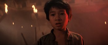 Movie still from “Indiana Jones and the Temple of Doom” (1984), directed by Steven Spielberg – A young asian boy in a dark room; Close Up shot, Low angle