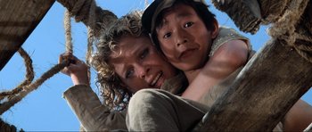 Movie still from “Indiana Jones and the Temple of Doom” (1984), directed by Steven Spielberg – A woman and a boy are hugging on a tree; Close Up shot, Low angle