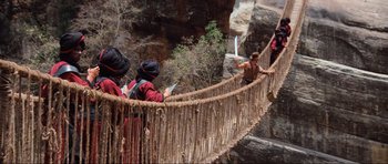 Movie still from “Indiana Jones and the Temple of Doom” (1984), directed by Steven Spielberg – A group of people standing on top of a wooden bridge; Wide shot, High angle