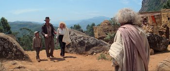 Movie still from “Indiana Jones and the Temple of Doom” (1984), directed by Steven Spielberg – A group of people standing on top of a dirt hill; Wide shot, Low angle