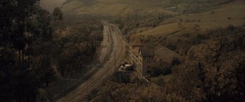 Movie still from “Infiesto” (2023), directed by Patxi Amezcua – An aerial view of train tracks near a building; Extreme Wide shot, High angle