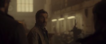 Movie still from “Infiesto” (2023), directed by Patxi Amezcua – A man with a beard is smiling for the camera; Close Up shot, Over the shoulder angle