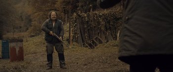 Movie still from “Infiesto” (2023), directed by Patxi Amezcua – A man holding a rifle in a field; Medium shot, Over the shoulder angle