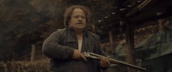 Movie still from “Infiesto” (2023), directed by Patxi Amezcua – A man holding a gun in his hands; Medium shot, Low angle