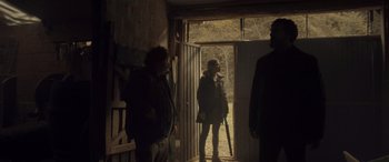 Movie still from “Infiesto” (2023), directed by Patxi Amezcua – A group of people standing in front of an open door; Wide shot, Over the shoulder angle