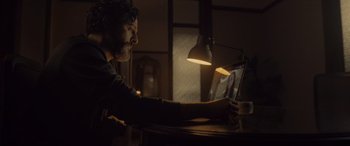 Movie still from “Infiesto” (2023), directed by Patxi Amezcua – A man sitting in front of a laptop computer; Medium shot, High angle