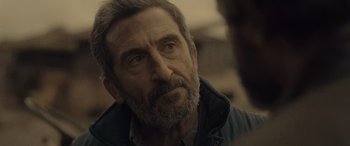 Movie still from “Infiesto” (2023), directed by Patxi Amezcua – An older man with a gray beard looking into the distance; Close Up shot, Over the shoulder angle