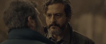 Movie still from “Infiesto” (2023), directed by Patxi Amezcua – A man with a gray beard is talking to another man; Close Up shot, Over the shoulder angle