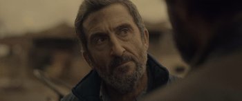 Movie still from “Infiesto” (2023), directed by Patxi Amezcua – An older man with a beard looking into the distance; Close Up shot, Over the shoulder angle