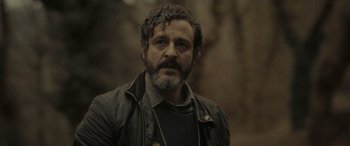 Movie still from “Infiesto” (2023), directed by Patxi Amezcua – A man with a goatee is looking at the camera; Close Up shot, Low angle