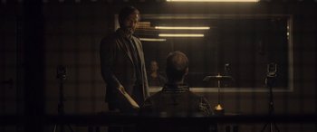 Movie still from “Infiesto” (2023), directed by Patxi Amezcua – A man standing in front of another man in a room; Medium shot, Over the shoulder angle