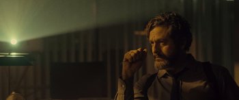 Movie still from “Infiesto” (2023), directed by Patxi Amezcua – A man with a beard is holding a cigarette in his hand; Close Up shot, Low angle