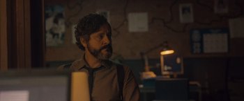 Movie still from “Infiesto” (2023), directed by Patxi Amezcua – A man with a beard is sitting in front of a computer; Close Up shot, Over the shoulder angle