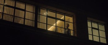 Movie still from “Infiesto” (2023), directed by Patxi Amezcua – A man looking out of a window at night; Wide shot, Low angle