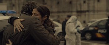 Movie still from “Infiesto” (2023), directed by Patxi Amezcua – Two people hugging each other in front of a building; Close Up shot, Over the shoulder angle