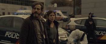 Movie still from “Infiesto” (2023), directed by Patxi Amezcua – A man and a woman standing next to each other on a street; Medium shot, Over the shoulder angle