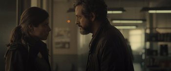 Movie still from “Infiesto” (2023), directed by Patxi Amezcua – A man standing next to another man in a room; Close Up shot, Over the shoulder angle