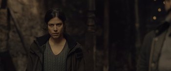 Movie still from “Infiesto” (2023), directed by Patxi Amezcua – A woman standing in the dark looking at the camera; Close Up shot, Over the shoulder angle