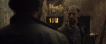 Movie still from “Infiesto” (2023), directed by Patxi Amezcua – A man standing in front of a fireplace talking to another man; Close Up shot, Over the shoulder angle