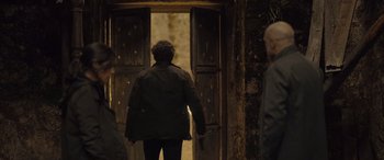 Movie still from “Infiesto” (2023), directed by Patxi Amezcua – A person walking in front of an open door; Medium shot, Over the shoulder angle