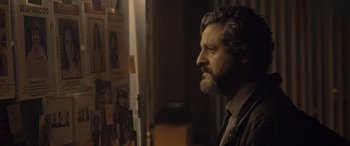 Movie still from “Infiesto” (2023), directed by Patxi Amezcua – A man standing in front of a window looking off to the side; Close Up shot, Over the shoulder angle