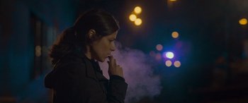 Movie still from “Infiesto” (2023), directed by Patxi Amezcua – A woman is smoking a cigarette in the dark; Close Up shot, Low angle