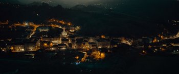 Movie still from “Infiesto” (2023), directed by Patxi Amezcua – An aerial view of a city lit up at night; Extreme Wide shot, High angle