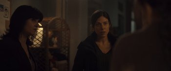 Movie still from “Infiesto” (2023), directed by Patxi Amezcua – A woman standing in front of a mirror in a dark room; Close Up shot, Over the shoulder angle