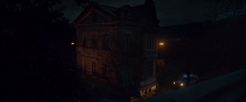 Movie still from “Infiesto” (2023), directed by Patxi Amezcua – An old building with a dark sky in the background; Extreme Wide shot, Low angle
