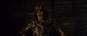 Movie still from “Infiesto” (2023), directed by Patxi Amezcua – An old man with a long beard wearing a fur coat; Close Up shot, Over the shoulder angle