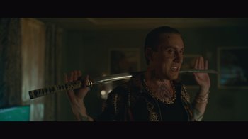Movie still from “Infinite” (2021), directed by Antoine Fuqua – A man holding a sword in a room; Close Up shot, Over the shoulder angle